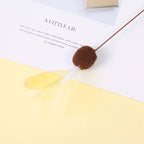 Brown pom-pom on a book with text and a yellow leaf