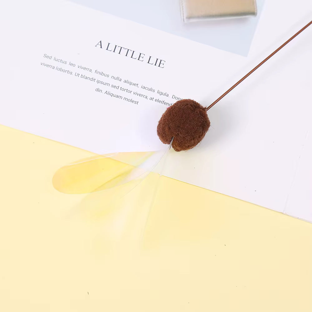 Brown pom-pom on a book with text and a yellow leaf