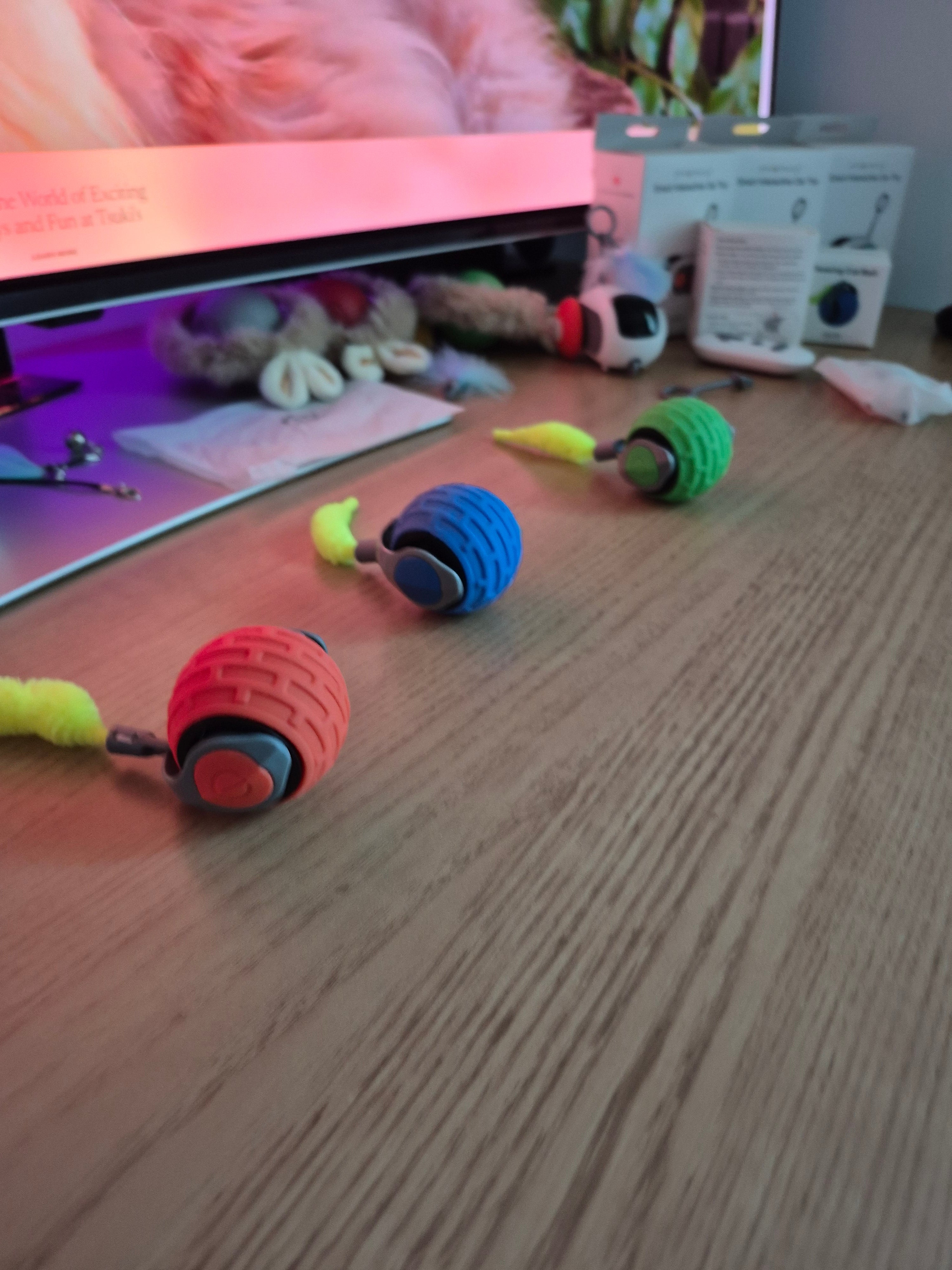 Colorful dog toys hanging on a wooden surface with a blurred background