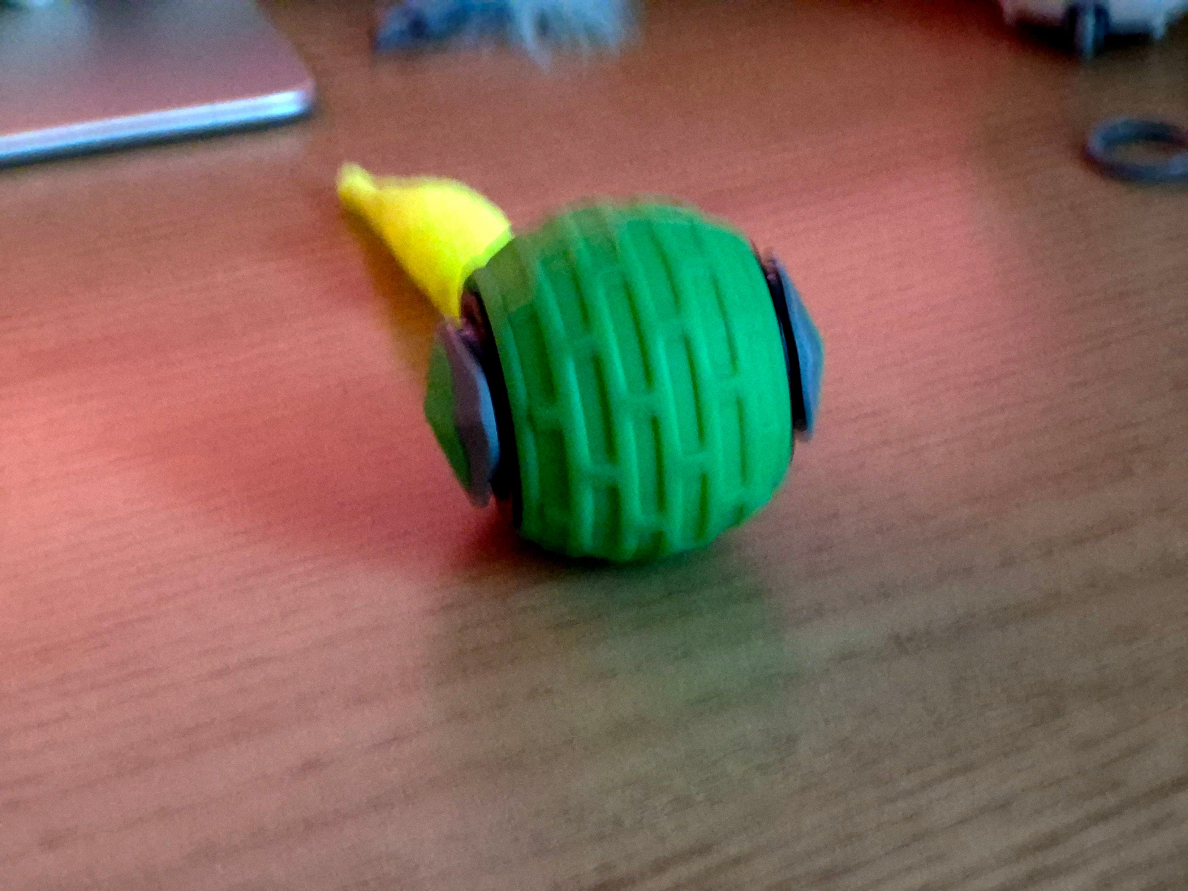 Green and yellow ball with black accents on a wooden surface