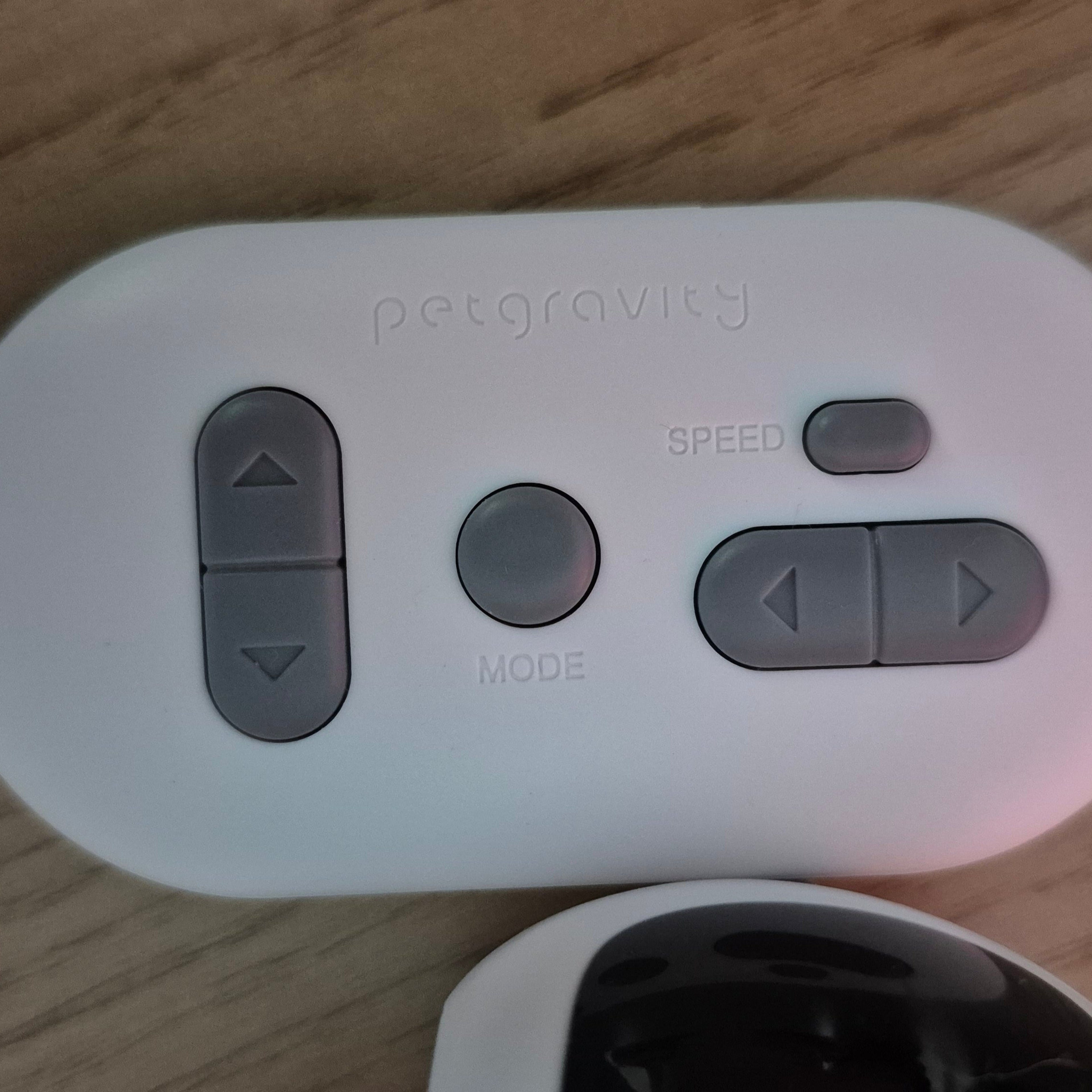 White remote control with gray buttons on a wooden surface